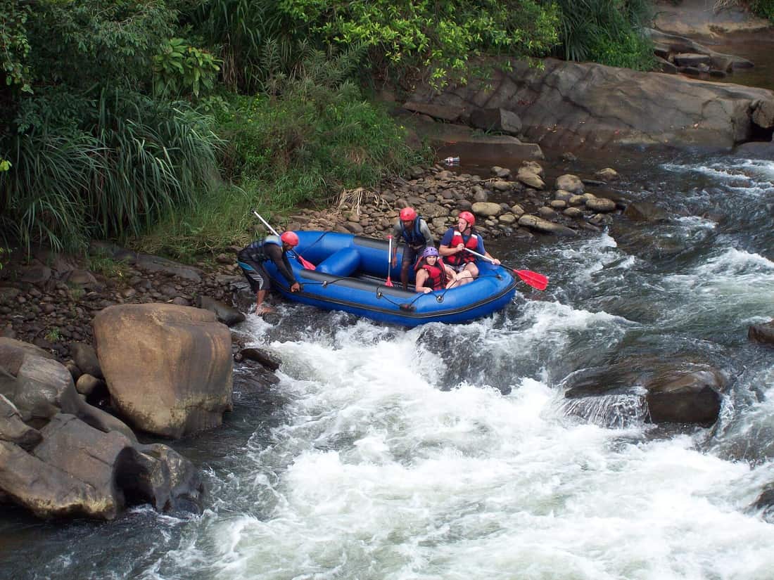 A raft of paddlers in helmets running a rapid on the Kelani River at Kitulgala