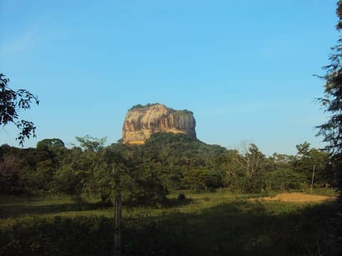 Sigiriya rock rising above the forest, seen across a clearing