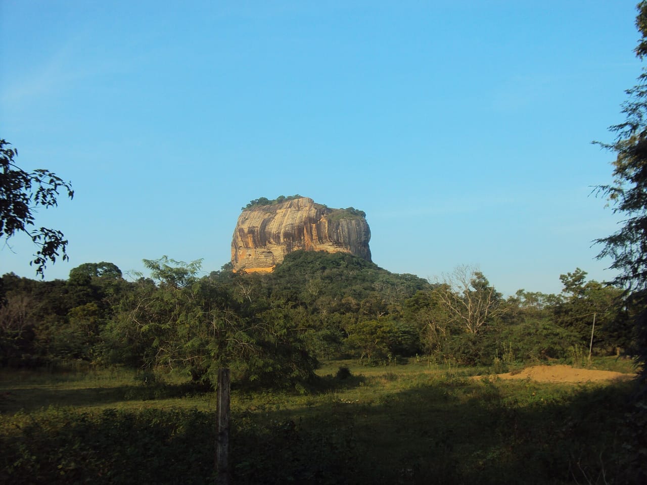 Sigiriya rock rising above the forest, seen across a clearing